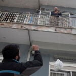 Un voluntario, Dimitris Pantzartzidis, saluda a Antonis a quien lleva comida porque él no puede salir de casa en Tesalónica, Grecia