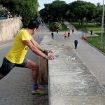 GRAFCVA4660. VALENCIA, 02/05/2020.- Un deportista realiza estiramientos mientras contempla el flujo de deportistas en el antiguo cauce del Turia dentro de la nueva normativa decretada por el Gobierno que permite hacer deporte o salir a pasear en dos franjas horarias. EFE/Kai Försterling