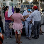 April 25, 2020 - Tijuana, Baja California, Mexico: Christian Acosta, center, who is coughing and clutching his chest, is surrounded by Pastor Samuel Hernandez, wearing a red cap, from Iglesia Evangelica Pentecostes, and other worshippers who are praying for his recovery, outside Tijuana General Hospital. Acosta says he's had breathing problems for the past 5 days and will seek treatment at a nearby clinic. (Marcus Yam / Los Angeles Times/Contacto)25/04/2020 ONLY FOR USE IN SPAIN