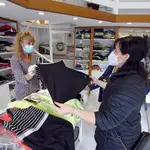 Una mujer atiende a una clienta en una tienda de ropa