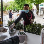 Un camarero coge varios cafés para servirlos en la terraza de un bar abierto en la Plaza de la Hispanidad de Cuenc