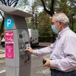 Un hombre introduce monedas en un parquímetro de la Ordenanza Reguladora del Aparcamiento (ORA)