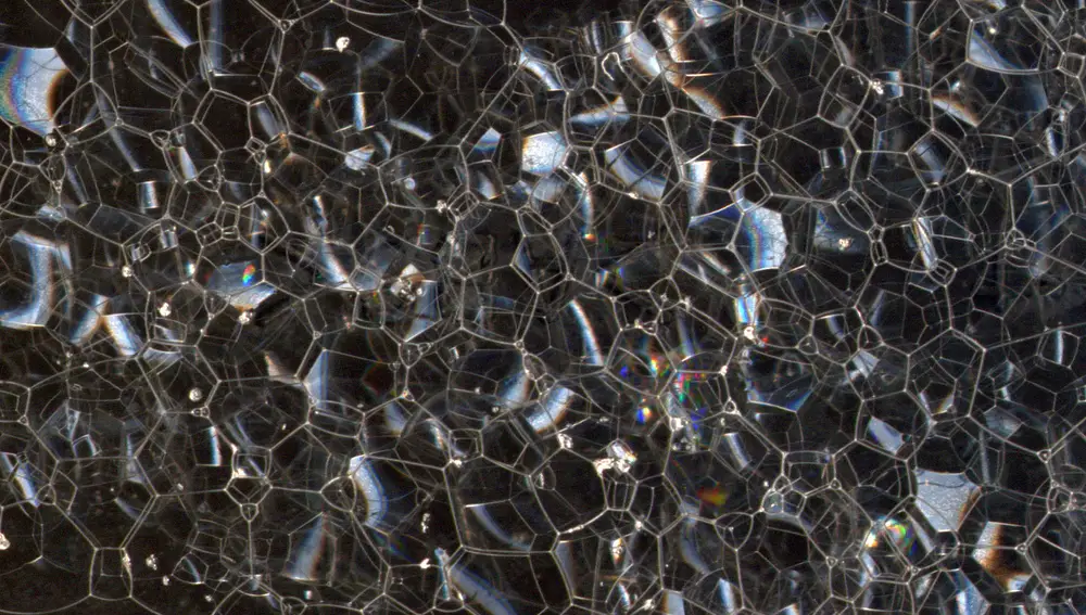 Según algunas teorías de gravedad cuántica el espacio-tiempo tendría, a escala microscópica, un aspecto similar a una espuma, como la que vemos en esta imagen. Estaría formado por “píxeles” del tamaño de la longitud de Planck, pero esos píxeles tendrían una estructura desordenada que afectaría al movimiento de los objetos. Podemos imaginar esos efectos pensando en que un objeto, para llegar de un punto A a un punto B, tendría que ir “saltando” de burbuja en burbuja, pasando cada vez a una de las burbujas adyacentes.