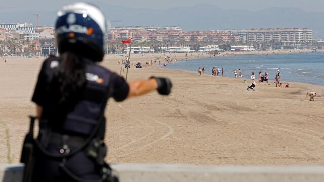 Una agente de la Policía Nacional realiza labores de control en la playa de la Malvarrosa