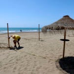 Un trabajador en la playa de Sacaba en la barriada de Huelín. Álex Zea / Europa Press