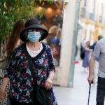 Una mujer pasea con mascarilla por una calle de la capital hispalense