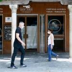 Dos personas, equipadas con mascarillas, se cruzan en una calle de Sevilla