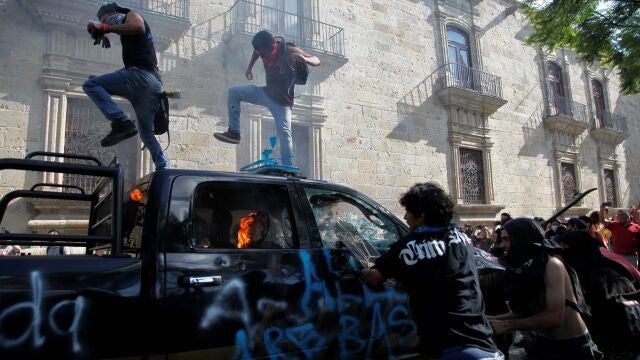 MEX2109. GUADALAJARA (MÉXICO), 04/06/2020.- Manifestantes brincan y destruyen una patrulla que arde tras ser quemada este jueves, durante una protesta por la muerte de Giovanni López, golpeado por policías de Ixtlahuacan de los Membrillos, en la ciudad de Guadalajara (México). Al menos 20 personas detenidas y dos patrullas incendiadas dejaron este jueves las protestas en la ciudad mexicana de Guadalajara en contra del abuso policial a un joven que murió tras ser arrestado por no usar tapabocas en plena pandemia por el coronavirus. EFE/Francisco Guasco