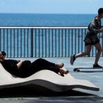 Una mujer toma el sol en el paseo marítimo de la Barceloneta este miércoles.