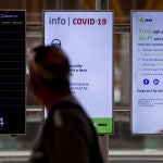 Un hombre pasa junto a unos paneles con información de la Covid-19 en el Aeropuerto de Adolfo Suárez Madrid-Barajas