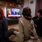 Tres personas ven el discurso extraordinario del rey Felipe VI, en un mensaje por televisión dirigido a los españoles en relación con la crisis del coronavirus después de reunirse en el Palacio de la Zarzuela con el presidente del Gobierno, Pedro Sánchez, y con los cuatro ministros que integran el Comité Técnico de Gestión de la pandemia.