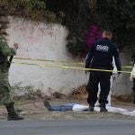 Integrantes de la Guardia Nacional, Policía Estatal y Servicios Periciales revisan el cuerpo de un hombre este domingo las calles de la ciudad de Apaseo El Alto en el estado de Guanajuato (México)