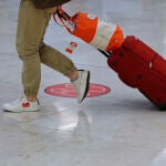 Un pasajero pasa junto a una de las señales circulares y rojas que marcan la distancia que deben guardar los usuarios entre ellos en el Aeropuerto de Madrid-Barajas Adolfo Suárez, como medida de control de los casos sospechosos de coronavirus cuatro días después desde que se decretase el final del estado de alarma a consecuencia del COVID-19, en Madrid (España), a 24 de junio de 2020.24 JUNIO 2020 MADRID-BARAJAS;CORONAVIRUSJesús Hellín / Europa Press24/06/2020