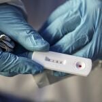 Healthcare worker Patricio Candia shows a rapid COVID-19 test with a positive result outside a supermarket in Santiago, Chile, Saturday, June 27, 2020.(AP Photo/Esteban Felix)