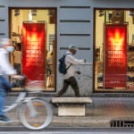 Varias personas pasan al lado del escaparate de una tienda donde se observan carteles indicativos de rebajas en Valencia