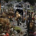 A musician walks between graves of people deceased in the last two months, in a section of the Municipal Cemetery of Valle de Chalco opened to accommodate the surge in deaths amid the ongoing coronavirus pandemic, on the outskirts of Mexico City, Thursday, July 2, 2020. (AP Photo/Rebecca Blackwell)