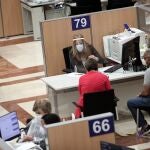Una trabajadora de la Oficina de la Agencia Tributaria en la Calle Guzmán el Bueno (Madrid) atiende a dos personas para confeccionar la declaración de la Renta de 2019