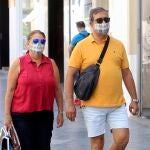 Transeúntes pasean por Sevilla, equipados con mascarillas, en una jornada de julio poco habitual
