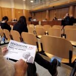 Una de las personas del público sostiene un cartel de una concentración convocada a las puertas de los juzgados, durante la primera jornada del juicio sobre la propiedad del Pazo de Meirás