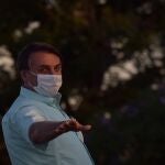 AME3901. BRASILIA (BRASIL), 22/07/2020.- El presidente de Brasil, Jair Bolsonaro, asiste este miércoles a la ceremonia diaria de arriada de la bandera en el Palacio da Alvorada, en Brasilia (Brasil). Bolsonaro, quien este miércoles volvió a dar positivo de coronavirus, enfermedad que le aqueja desde el pasado 7 de julio, se mostró de buen humor en un breve encuentro con una veintena de simpatizantes. Pese al tercer positivo en igual número de exámenes realizados durante los últimos quince días, el líder de la ultraderecha volvió a conversar con algunos partidarios en los jardines de su residencia oficial, separado por un pequeño canal de agua de unos tres metros de ancho. EFE/Andre Borges