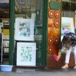 Una mujer limpia la fachada de su comercio en Ponferrada