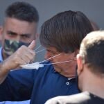 El presidente de Brasil, Jair Bolsonaro, se quita la mascarilla
