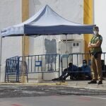 Un policía y un guarida de seguridad vigilan a un grupo de inmigrantes indocumentados que consiguieron saltar la valla este jueves en Melilla. EFE/Paqui Sánchez