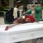 Una mujer abraza uno de los ataúdes colocados en la calle para rechazar las recientes masacres en Colombia