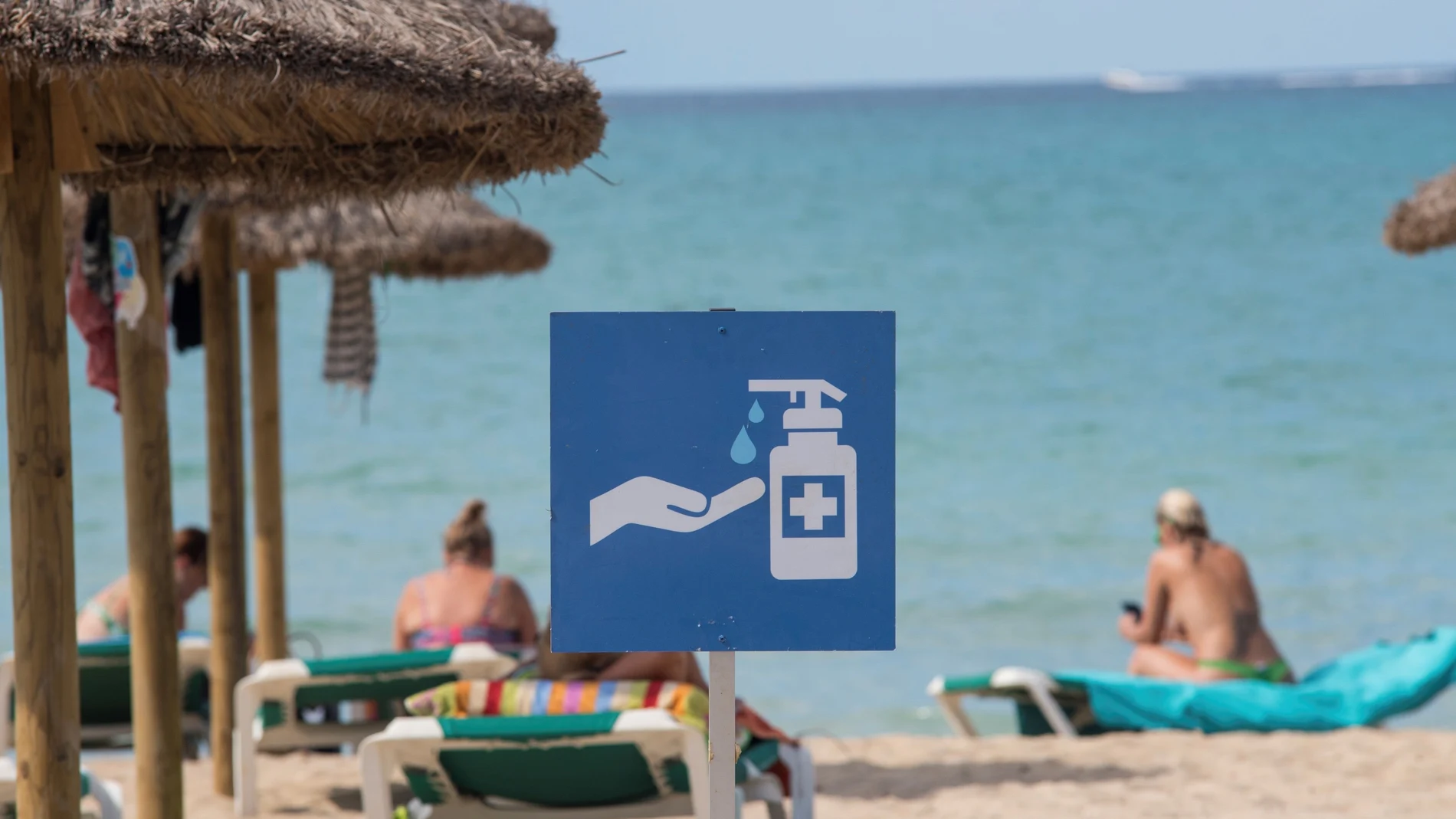 Un cartel en la playa de Palma de Mallorca recuerda la necesidad de usar gel desinfectante para evitar contagios