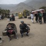 A cemetery worker sits in his wheelbarrow during his lunch breaj as fellow workers walk past shouldering a casket that contains the remains of a person who is suspected to have died from symptoms related to the new coronavirus, at the "Martires 19 de Julio" cemetery, in Comas, on the outskirts of Lima, Peru, Saturday, July 4, 2020. Along with cremations, burials have continued, with nearly 200 deaths daily due to a rate of infection that continues to be among the worldâ€™s highest. Many families must hunt down spots in economical and far-flung cemeteries on the outskirts of Lima. (AP Photo/Rodrigo Abd)