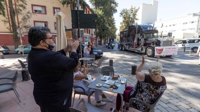 Varios clientes de una cafeteria de Murcia aplauden el paso de la caravana de coches convocada por la Asociación de Hosteleros de Murcia (Hostemur) durante una manifestación por las calles del centro de la ciudad