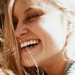 En la imagen, una mujer sonríe y presume de dientes blancos.