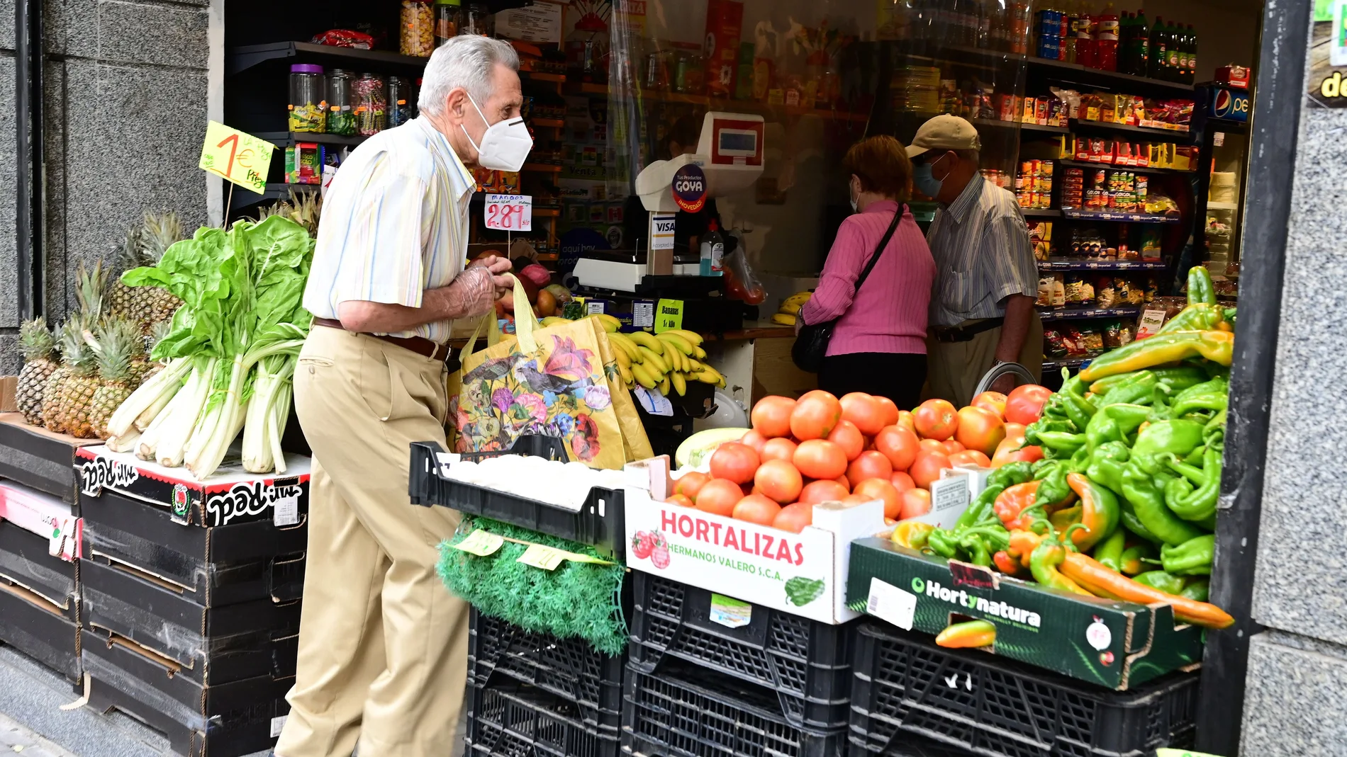 Vecinos del distrito del Puente de Vallecas hacen sus compras en una frutería en la Avenida de la Albufera, en Madrid