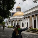 AME8749. CARACAS (VENEZUELA), 01/10/2020.- Fotografía de archivo fechada el 1 de julio de 2020 que muestra a una mujer mientras camina frente al palacio federal legislativo de la Asamblea Nacional, en Caracas (Venezuela). El Gobierno de Nicolás Maduro dejó claro este jueves que no admitirá el condicionamiento de la Unión Europea (UE) de retrasar unos meses las elecciones legislativas de diciembre, para participar como observadores en estos comicios, que Venezuela prevé celebrar pese a múltiples cuestionamientos. EFE/ Miguel Gutierrez ARCHIVO