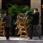 Dos trabajadores recogen la terraza de un bar del centro de Barcelona este viernes poco después de que el Tribunal Superior de Justicia de Cataluña avalara las restricciones