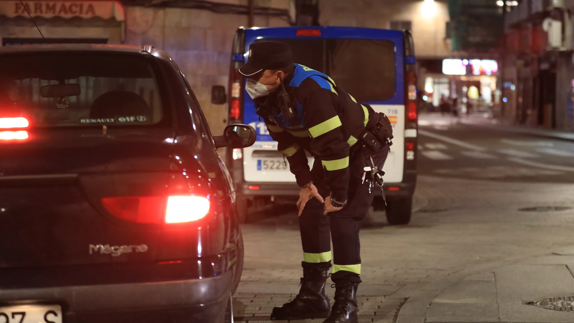 Un policía local se acerca a hablar con ciudadanos que están en un coche en Salamanca