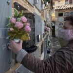 Una mujer coloca flores de plástico en la lápida de un familiar en el cementerio de San Eufrasio de Jaén. EFE/José Manuel Pedrosa.