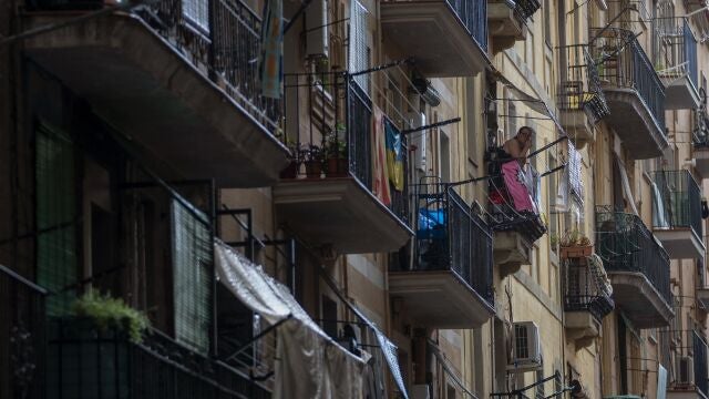 Una mujer fuma en el balcón de su vivienda, ubicada en un popular barrio de Barcelona