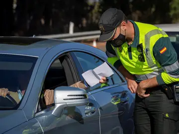 Un agente de la Guardia Civil de Tráfico comprueba un documento aportado por un conductor durante un control establecido en la autopista AP-4 Sevilla-Cádiz Un agente de la Guardia Civil de Tráfico comprueba un documento aportado por un conductor durante un control establecido en la autopista AP-4 Sevilla-Cádiz