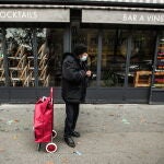 Un anciano con mascarilla, junto a un restaurante cerrado, en París