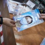 Una farmacéutica enseña a un cliente un paquete de mascarillas