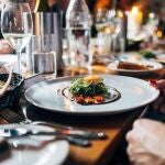 En la imagen, una mujer cenando en un restaurante.
