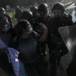 A couple of demonstrators scuffle with police outside of La Moneda presidential palace during a protest against President Sebastian Pi��era, demanding his resignation, in Santiago, Chile, Wednesday, Nov. 18, 2020. (AP Photo/Esteban Felix)