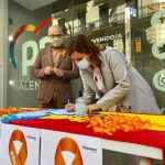 María José Catalá firma ante la atenta mirada del senador Fernando de Rosa