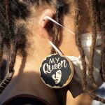 Una mujer ataviada con una mascarilla, luce unos pendientes de la política y activista afroamericana Angela Davis con la frase "My Queen" (Mi reina) durante la celebración este sábado de la emancipación de la comunidad negra de Estados Unidos