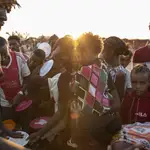 Refugiados de Tigray que huyeron del conflicto en la región de Tigray de Etiopía, esperan a que voluntarios locales sudaneses les sirvan arroz cocido en el campamento de refugiados de Um Rakuba en Qadarif, en el este de Sudán