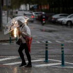 Una mujer camina protegida de la lluvia con un paraguas