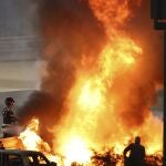 Staff extinguish flames from Haas driver Romain Grosjean of France's car after a crash during the Formula One race in Bahrain International Circuit in Sakhir, Bahrain, Sunday, Nov. 29, 2020. (Brynn Lennon, Pool via AP)