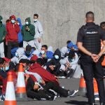 Varios inmigrantes descansan en el muelle de Arguineguín tras ser rescatados por Salvamento Marítimo en Gran Canaria el pasado diciembre