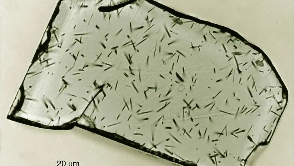 Imagen de un cristal de apatita pulido y tintado químicamente para hacer visibles las trazas nucleares cerca de su superficie. Cada una de las pequeñas líneas negras ha sido producida por una fisión de un átomo de uranio, la mayoría de ellas hace millones de años.